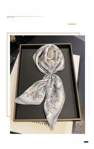 Detailed view of silver silk square scarf with colorful butterfly print in a gift box