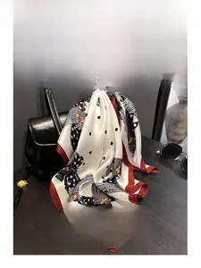 Dettaglio di un foulard in seta bianca a pois neri con bordi a scacchi rossi e neri