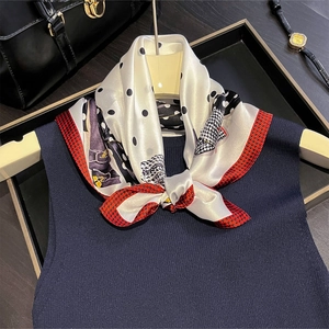 Foulard classico in seta a pois e quadri annodato su un top in maglia blu scuro