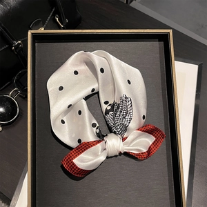 Dettaglio di un foulard in seta con pois neri, motivi pied de poule e nodo a fiocco