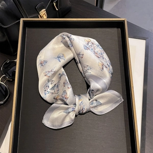Silk square scarf with butterfly print and purple edges on a luxury tray display