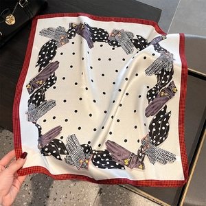 Dettaglio di un foulard in seta a pois neri con motivi a fiocco e bordo pied de poule