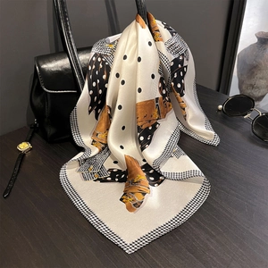 Dettaglio di un foulard in seta a pois e stampe equestri appeso a una borsa di lusso