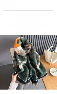 Detail of green landscape print imitation cashmere scarf with tassels on a wooden surface