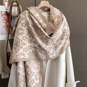 Close-up of floral jacquard patterns and delicate fringe on thick beige cashmere scarf
