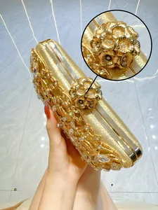 Detailed view of luxury gold evening clutch with hollow carving and rhinestone floral clasp