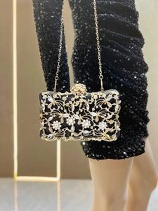 Close-up of gold filigree clutch bag with crystal floral pattern on black luxury fabric