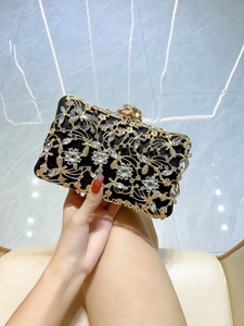 Macro view of crystal embellished floral metal patterns on the black evening clutch bag