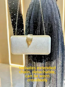 Close-up of evening clutch with gold leaf clasp and detachable chain strap on black dress