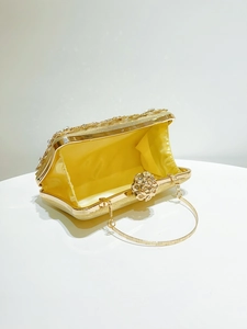 Detail of gold evening clutch with floral rhinestone clasp and glitter finish