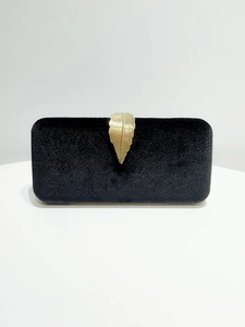 Detailed close-up of a black velvet evening clutch featuring a golden leaf metal buckle