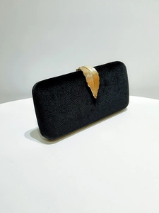 Detailed close-up of black velvet evening bag featuring a gold feather metal clasp