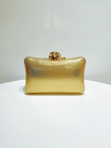 Macro shot of gold evening clutch featuring a rose metal clasp and glitter texture