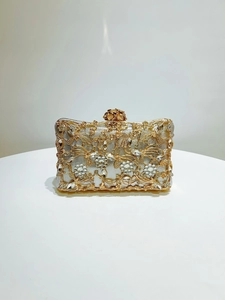 Detail of golden floral filigree evening bag with rhinestones and a 3D rose clasp