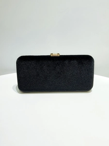 Detail of black velvet evening clutch with a polished gold rectangular metal clasp