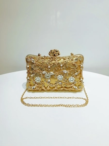 Detail of gold luxury evening clutch with intricate rhinestone flowers and metal clasp