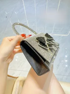 Close-up of luxury silver rhinestone evening bag with elegant black bow and round handle