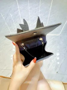 Detailed interior of a black sequin evening bag showing wide opening and metal chain