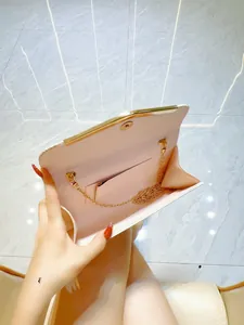 Detail view of pink satin evening clutch interior with gold chain and inner pocket