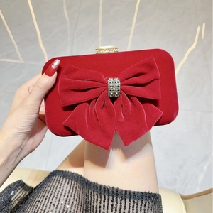 Close-up of burgundy velvet evening clutch featuring a rhinestone bow and metal clasp