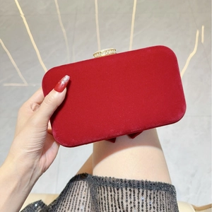 Macro detail of wine red velvet evening clutch with sparkling diamond-encrusted gold buckle