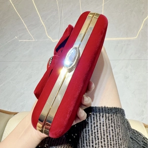 Detail of red velvet evening clutch featuring gold metal frame and crystal clasp