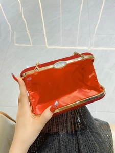 Macro view of red velvet evening bag with gold clasp, gemstone inlay and metal chain