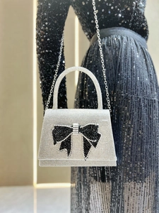 Detail of silver rhinestone evening bag featuring a large black crystal bow and chain