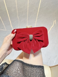 Close-up of a red velvet evening clutch featuring a crystal bow detail and metallic snap