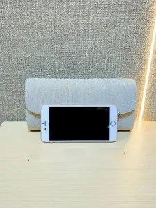 Detailed size comparison of a silver pleated evening clutch bag with a smartphone