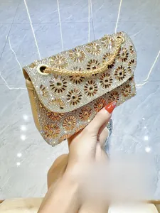 Detailopname van een strass avondtas met zonnebloempatroon en gouden ketting