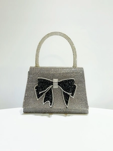 Macro shot of silver rhinestone surface and black crystal bow detail on evening clutch bag
