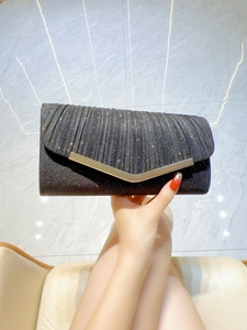 Detail of black pleated evening clutch with sparkling glitter and V-shaped gold trim