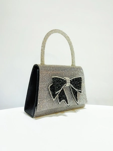 Detailed view of silver rhinestone handbag with a large black crystal bow decoration
