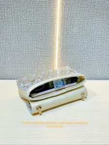 Detail van de gouden strass avondtas met een smartphone en make-up benodigdheden