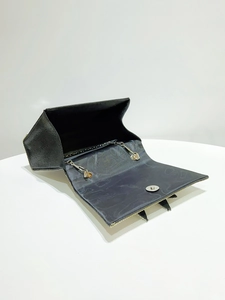 Detail view of black evening bag interior with metal chain strap and magnetic closure
