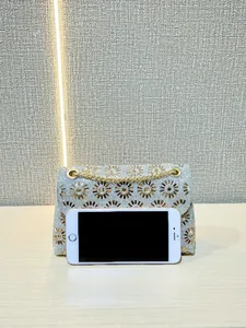 Detail van zilveren avondtas met strass, gouden bloemkristallen en kettingriem