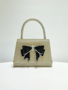Macro detail of silver rhinestone evening bag with elegant black crystal bow decoration
