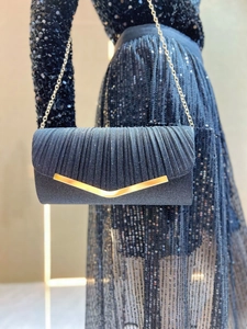 Detail of navy pleated evening clutch bag with gold V-shaped metal clasp and chain