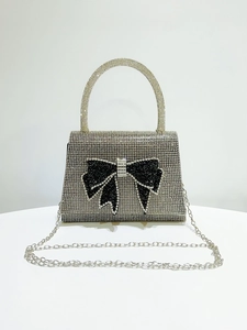 Close-up of a silver rhinestone evening bag featuring a large black crystal bow decoration
