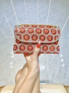 Detail van een sprankelende clutch met oranje en zilveren strassteentjes en bloemmotief