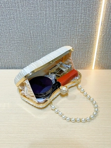 Detailed interior of satin pleated evening bag showing capacity for lipstick and perfume