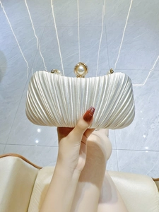 Detail view of a cream satin pleated evening clutch bag with large pearl clasp and chain