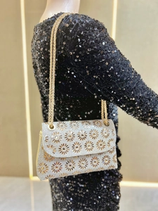 Detail van luxe strass clutch met gouden ketting op een zwarte avondjurk