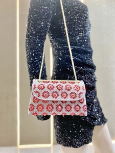 Detail van rode strass avondtas met bloemmotieven en een elegante gouden schouderketting