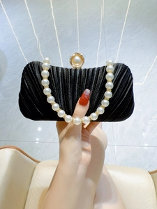 Detailed view of black pleated satin evening bag with large pearl clasp and handle