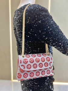 Detailopname van rode bloemen strass kettingtas op een zwarte paillettenjurik voor avond