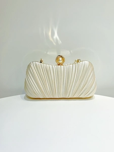 Close-up of cream pleated satin evening clutch with pearl and gold rhinestone clasp