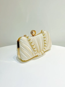 Detailed view of cream satin pleated evening bag with pearl rhinestone clasp and handle
