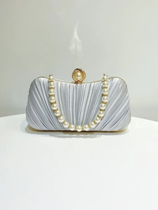 Macro shot of silver pleated satin evening clutch with pearl handle and round pearl metal clasp
